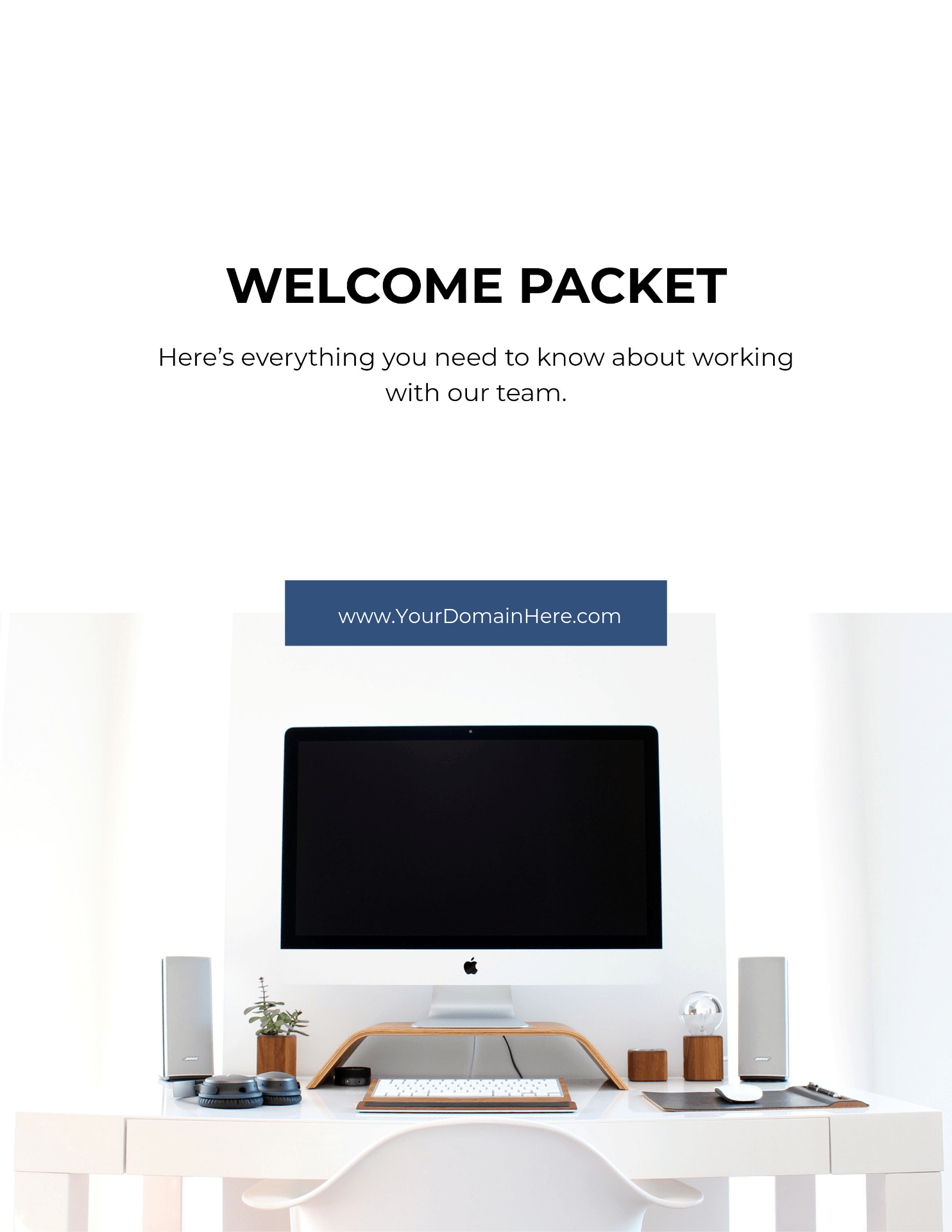 A white desk with a computer on it and a welcome packet.