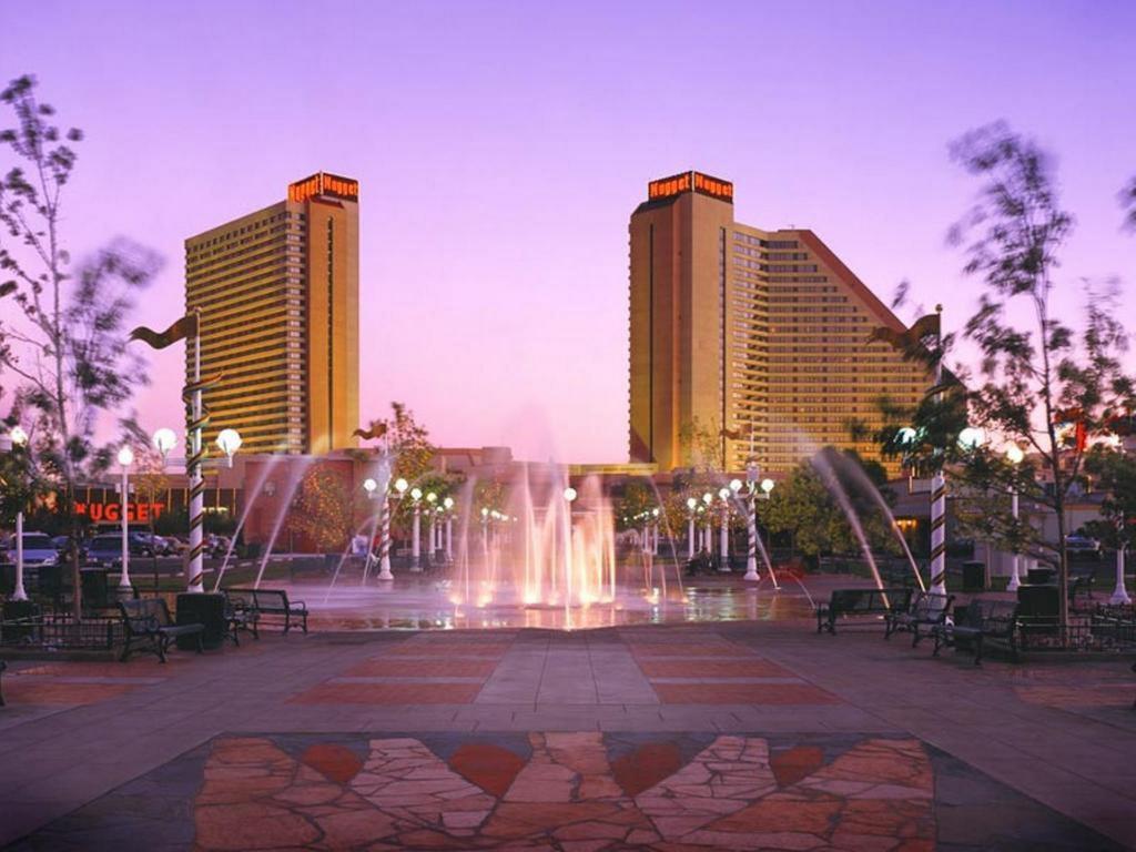 A fountain in a park with a hotel in the background