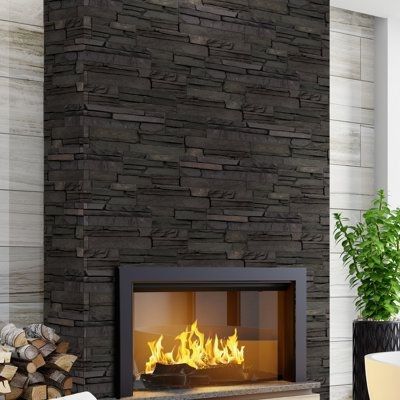 A fireplace in a living room with a black stone wall.
