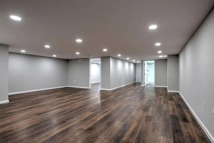 An empty basement with hardwood floors and gray walls.