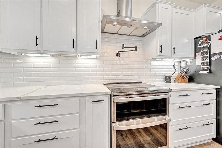 A kitchen with white cabinets and stainless steel appliances.