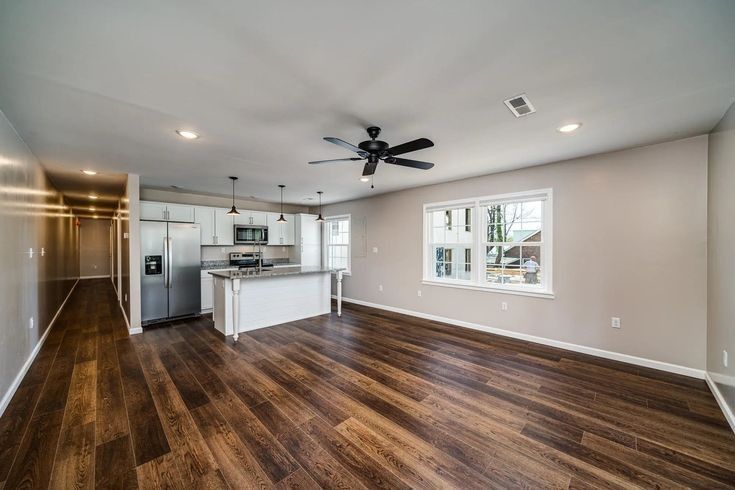 An empty living room with hardwood floors and a ceiling fan.