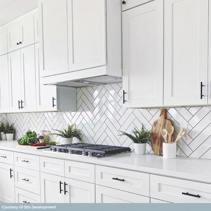 A kitchen with white cabinets and a stove top oven