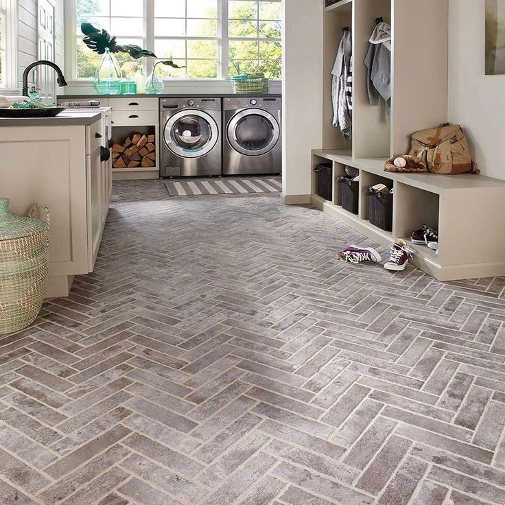 A laundry room with a herringbone floor and a washer and dryer.