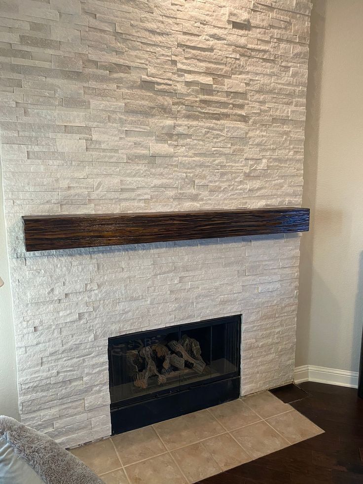 A white brick fireplace with a wooden mantle in a living room.