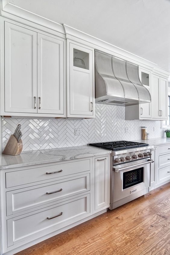 A kitchen with white cabinets , stainless steel appliances , and hardwood floors.