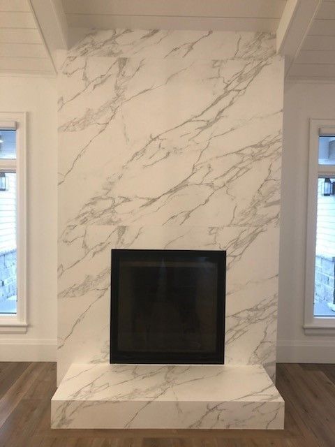 A fireplace in a living room with a marble wall