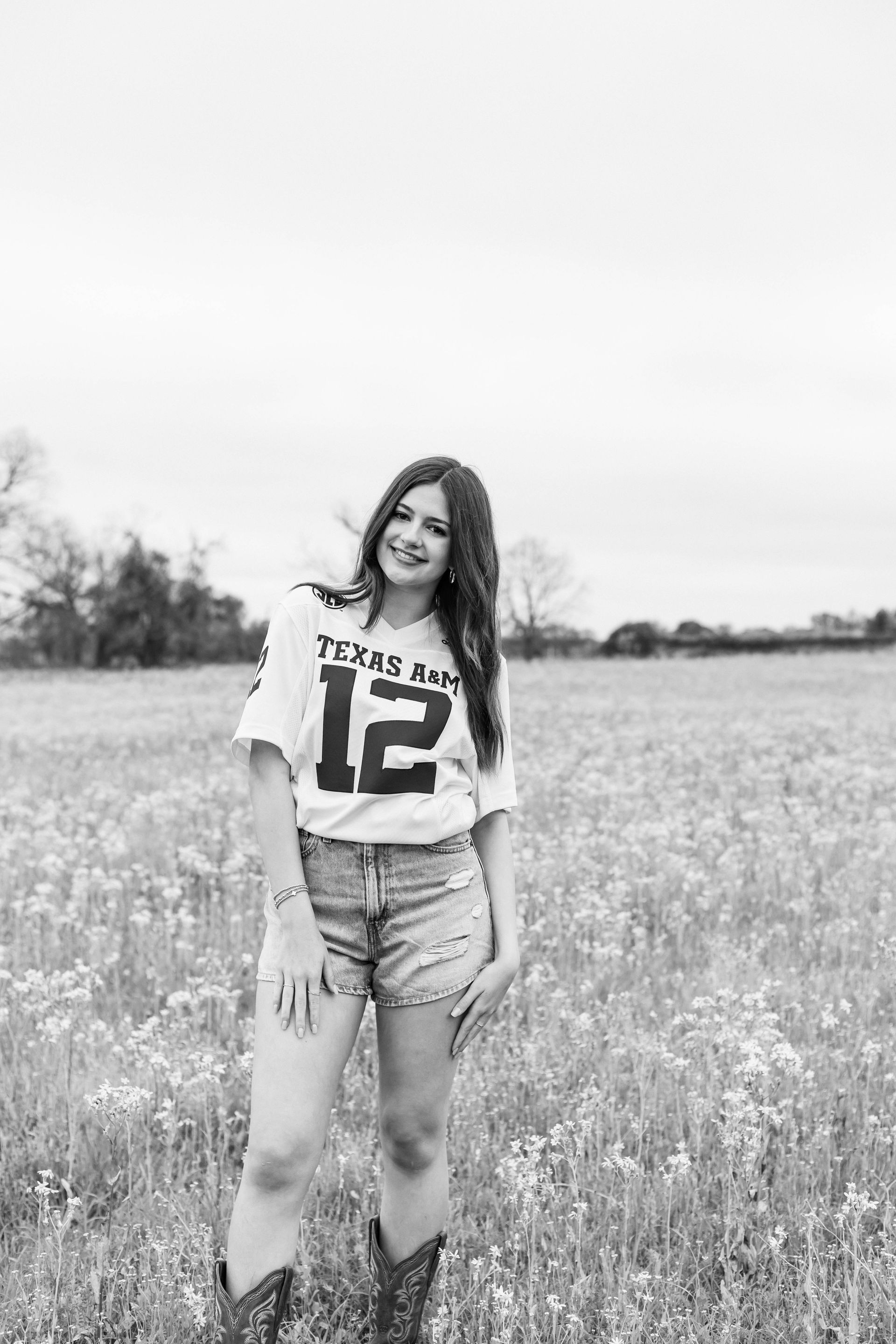 A black and white photo of a woman standing in a field.