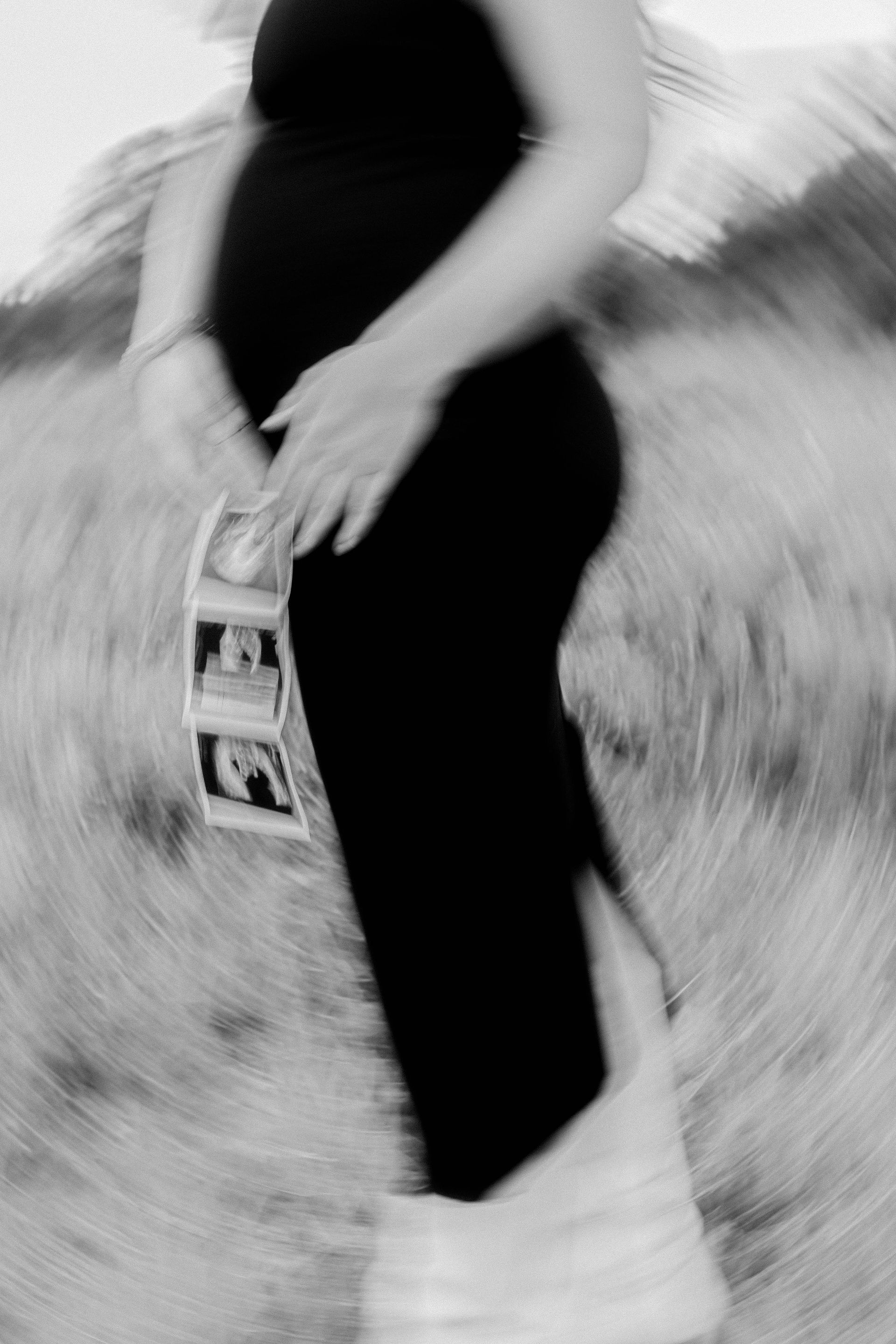 A black and white photo of a pregnant woman holding her belly.