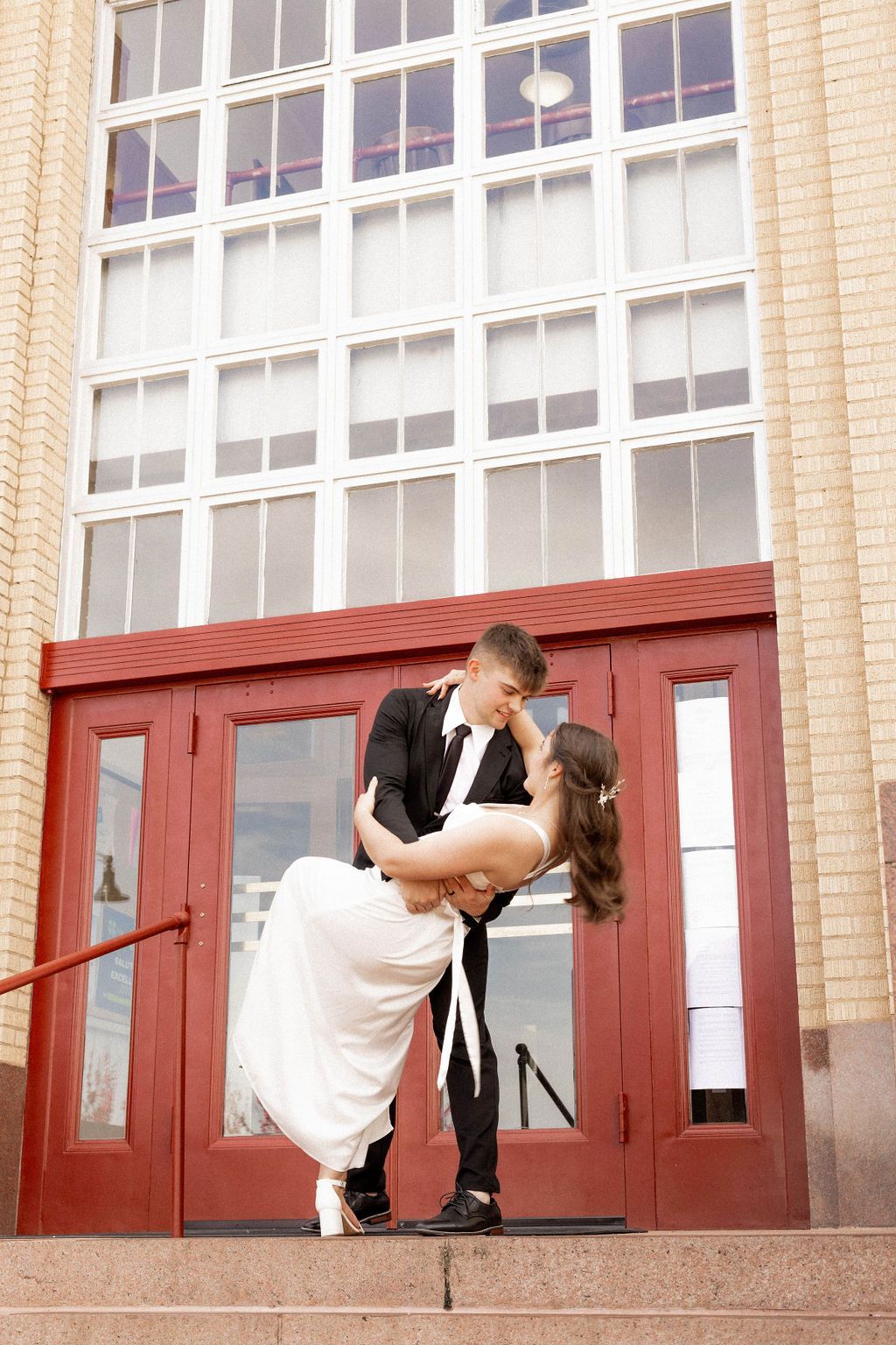 A man is holding a woman in his arms in front of a building.