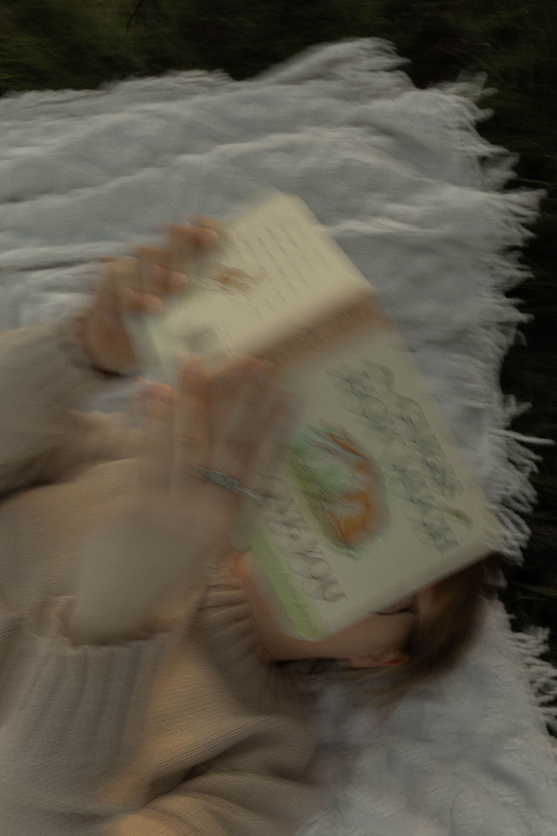 A person is laying on a bed reading a book.