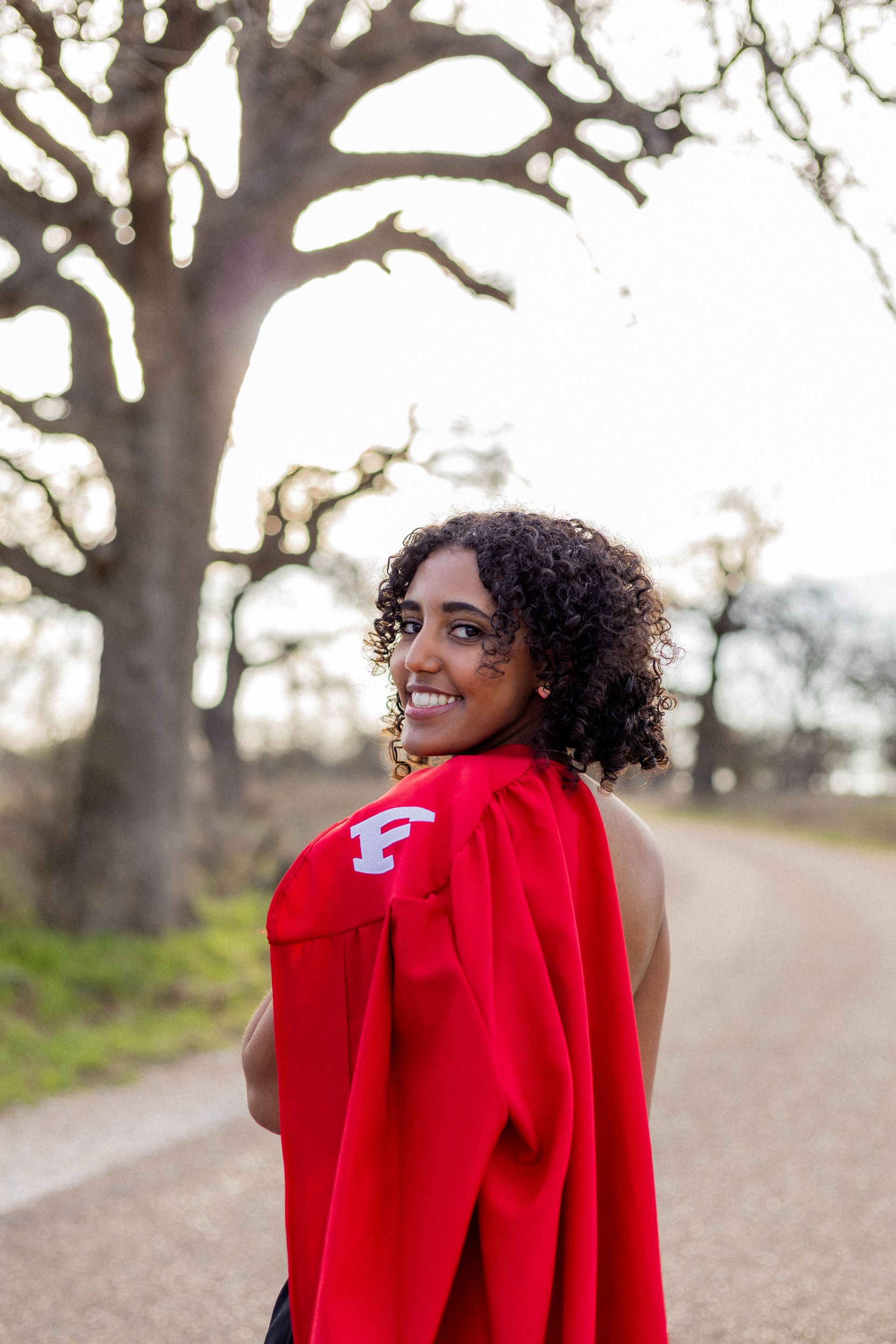 A woman is wearing a red cape with the letter f on it.