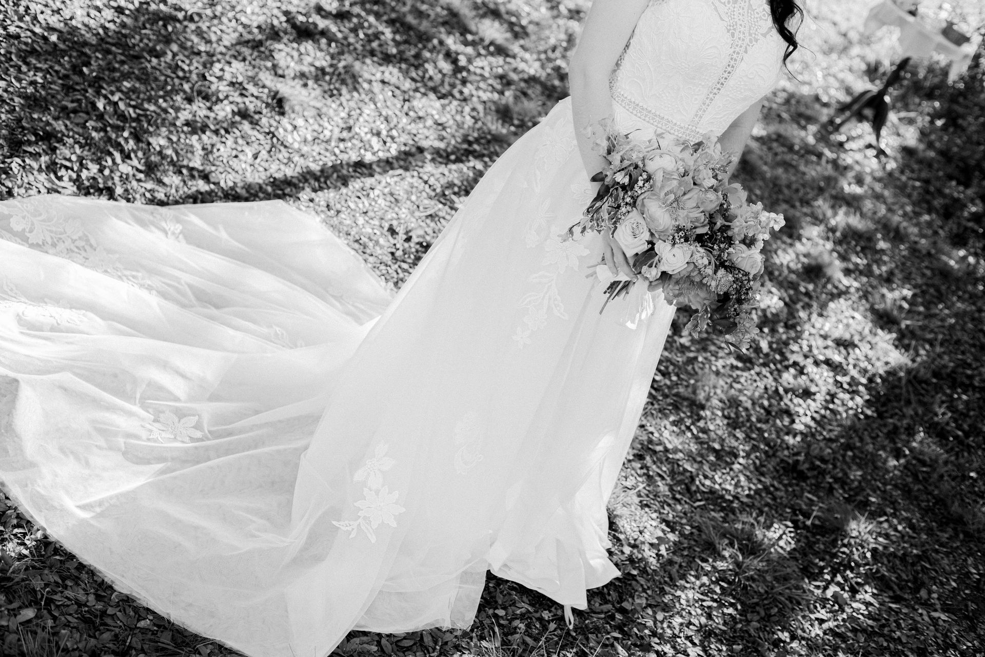 A black and white photo of a bride in a wedding dress holding a bouquet of flowers.