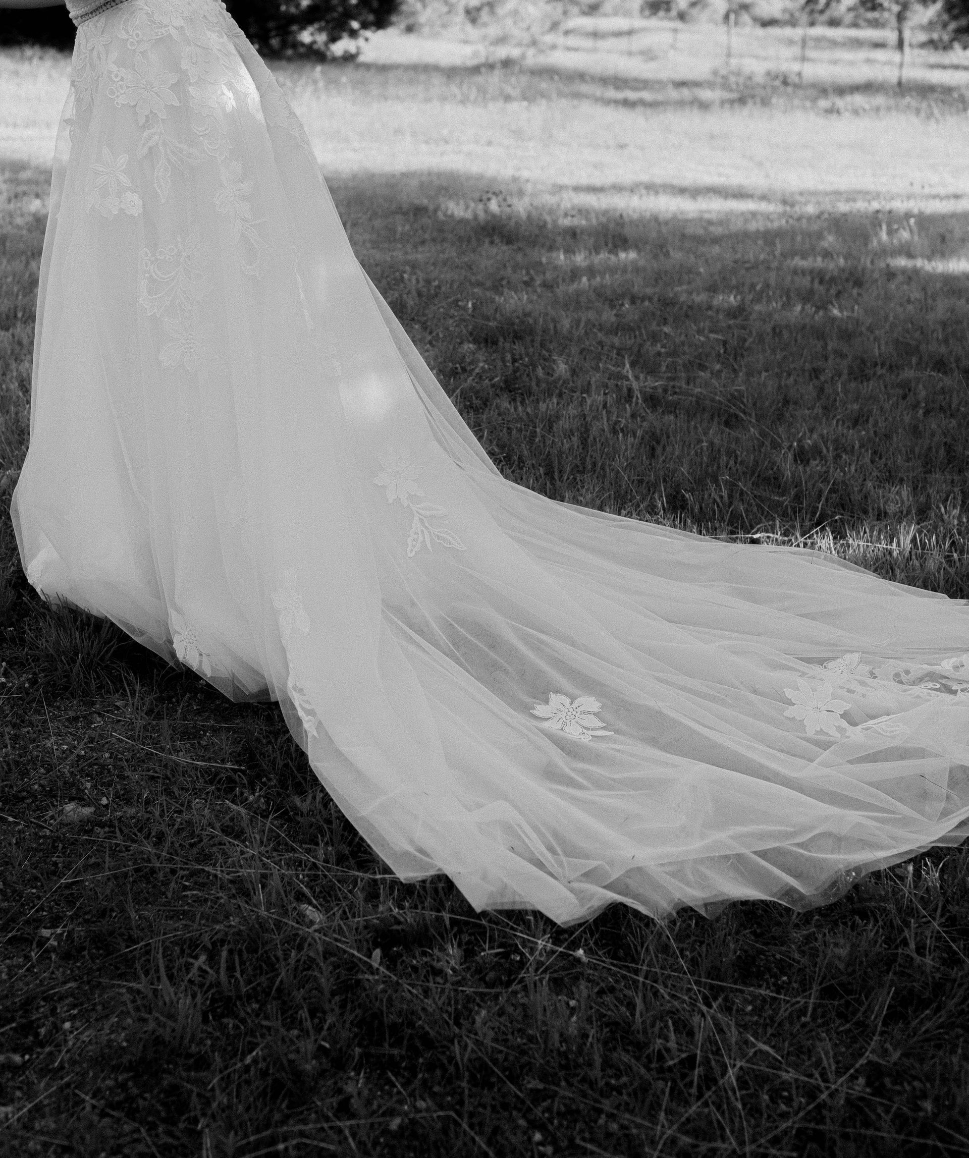 A black and white photo of a bride in a wedding dress with a long train.