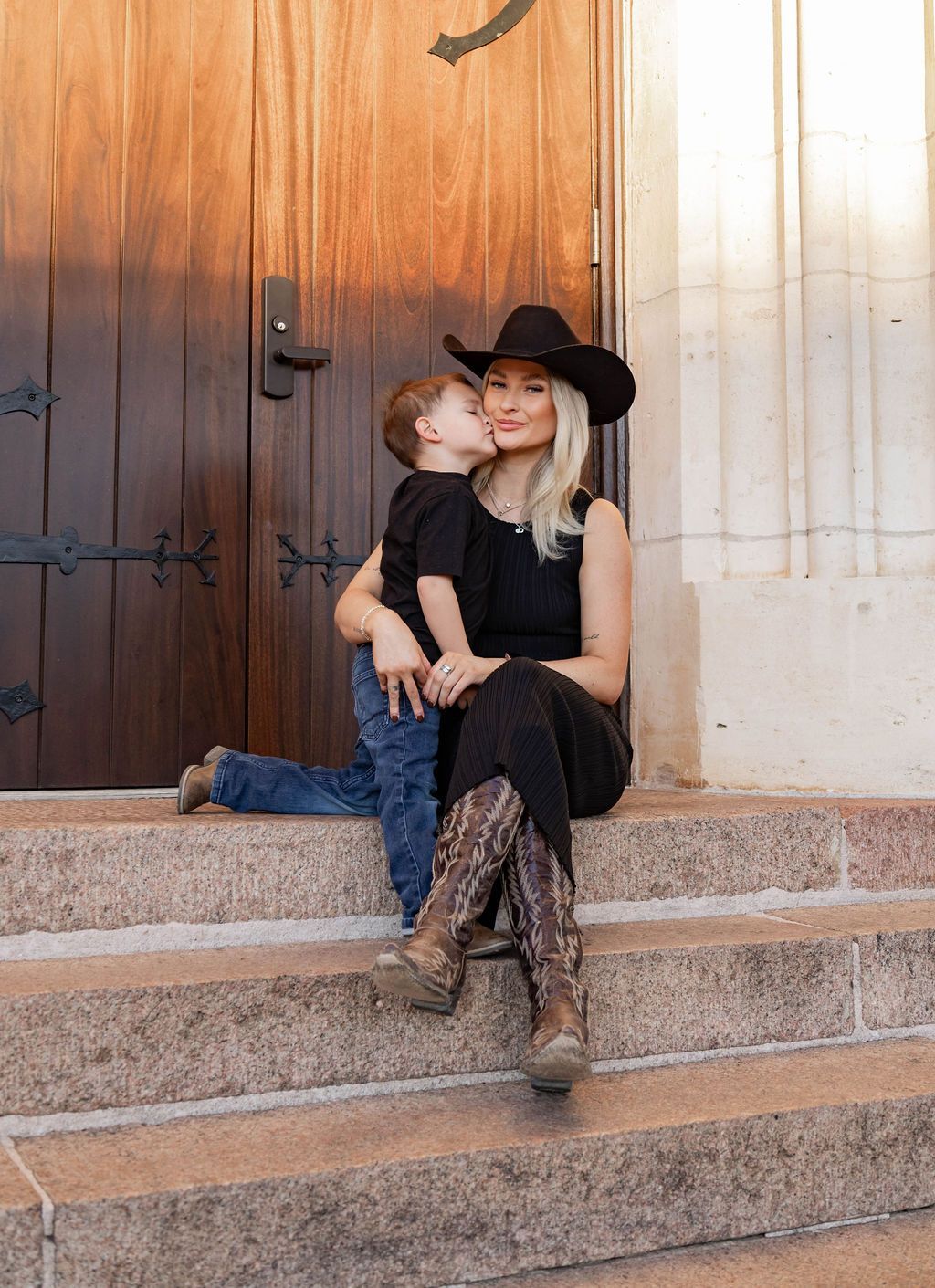 A woman and a child are sitting on the steps of a building.