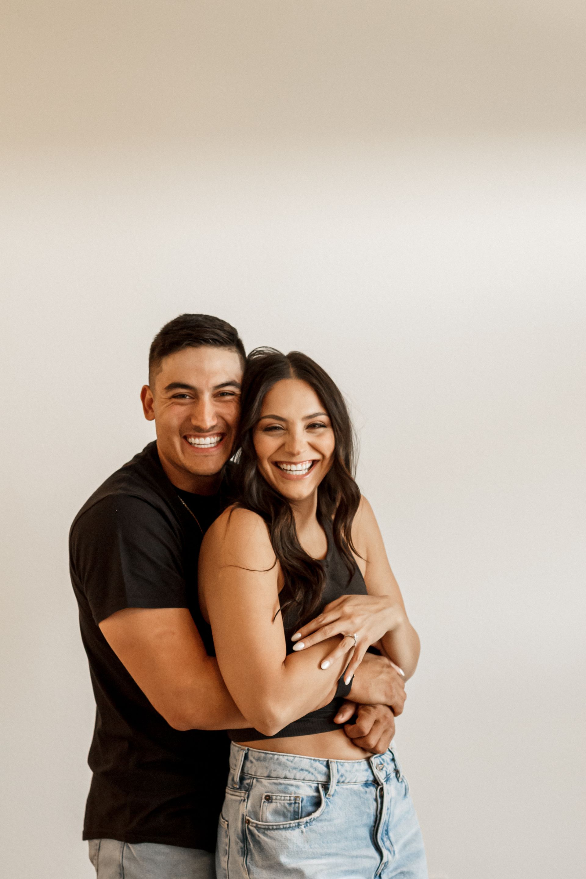 A man and a woman are hugging each other and smiling.