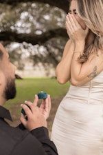 A man is proposing to a woman in a park.