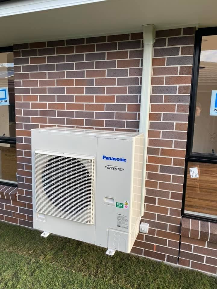 Panasonic Air Conditioner Unit Mounted on a Brick Wall, With a White Vent Pipe — Airset Air Conditioning in Urunga, NSW