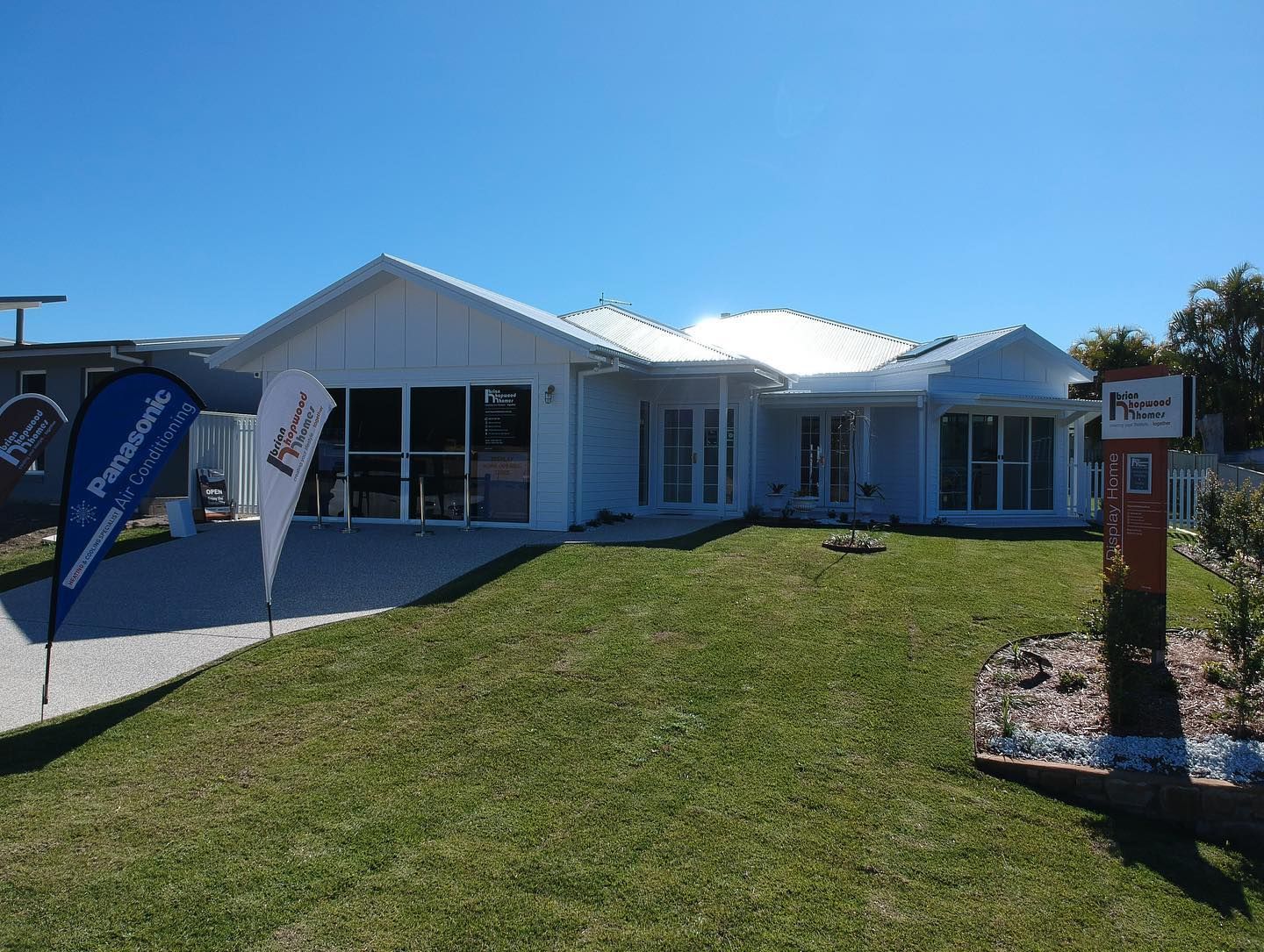 White House With Glass Windows on a Green Lawn, Two Flags, Sunny Day — Airset Air Conditioning in Bonville, NSW