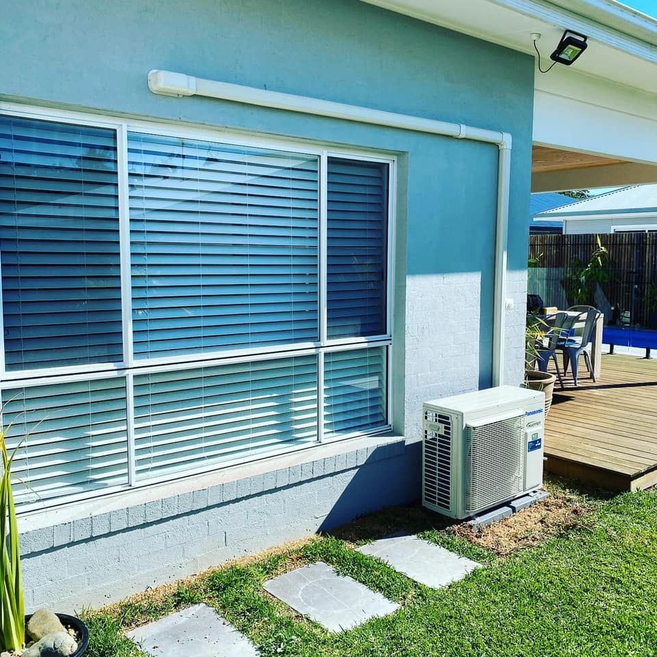 Air Conditioning Unit Outside a Blue House, Next to a Window — Airset Air Conditioning in Bonville, NSW