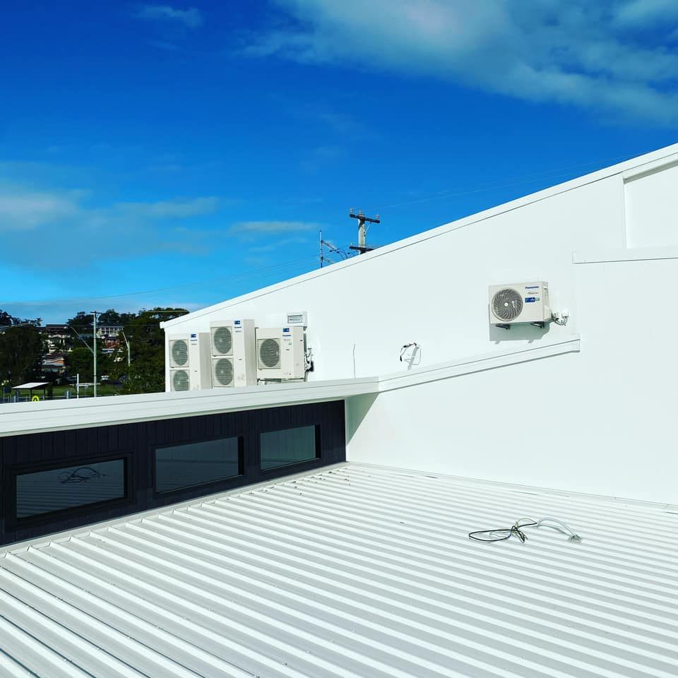 White rooftop with several air-conditioning units under a bright blue sky — Airset Air Conditioning in Macksville, NSW