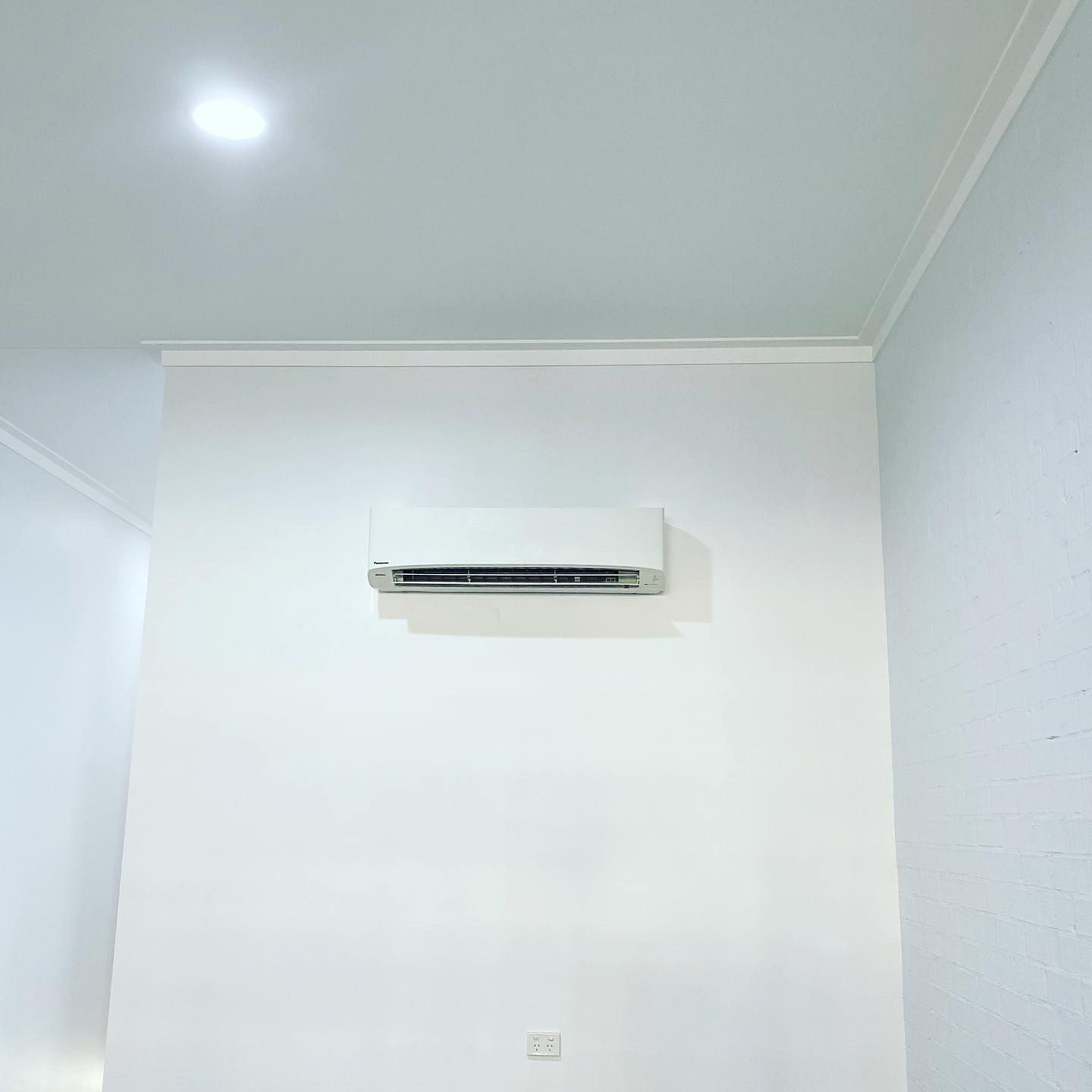 White room corner with a wall-mounted air conditioner near the ceiling — Airset Air Conditioning in Macksville, NSW