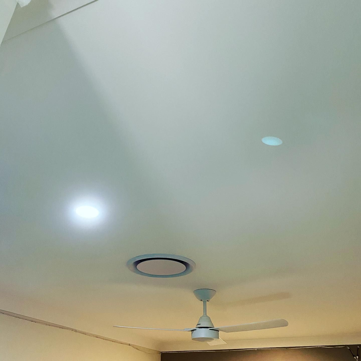 Ceiling with a fan, recessed light, and circular vent in a pale room — Airset Air Conditioning in Macksville, NSW