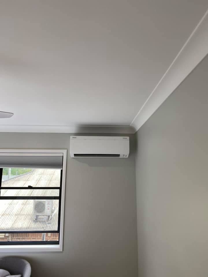 Air Conditioning Unit Mounted on a Gray Wall Above a Window — Airset Air Conditioning in Macksville, NSW