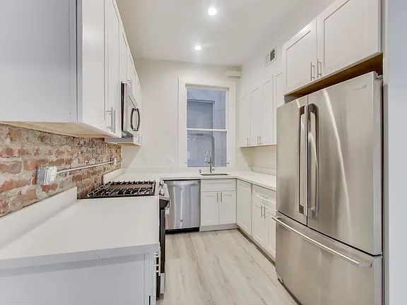 A kitchen with stainless steel appliances and white cabinets.