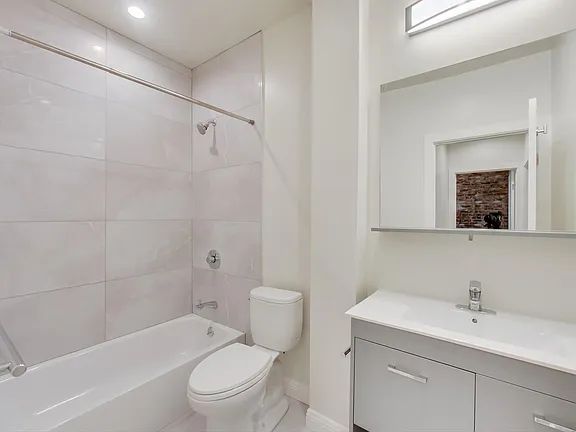 A bathroom with a toilet , sink , bathtub and mirror.