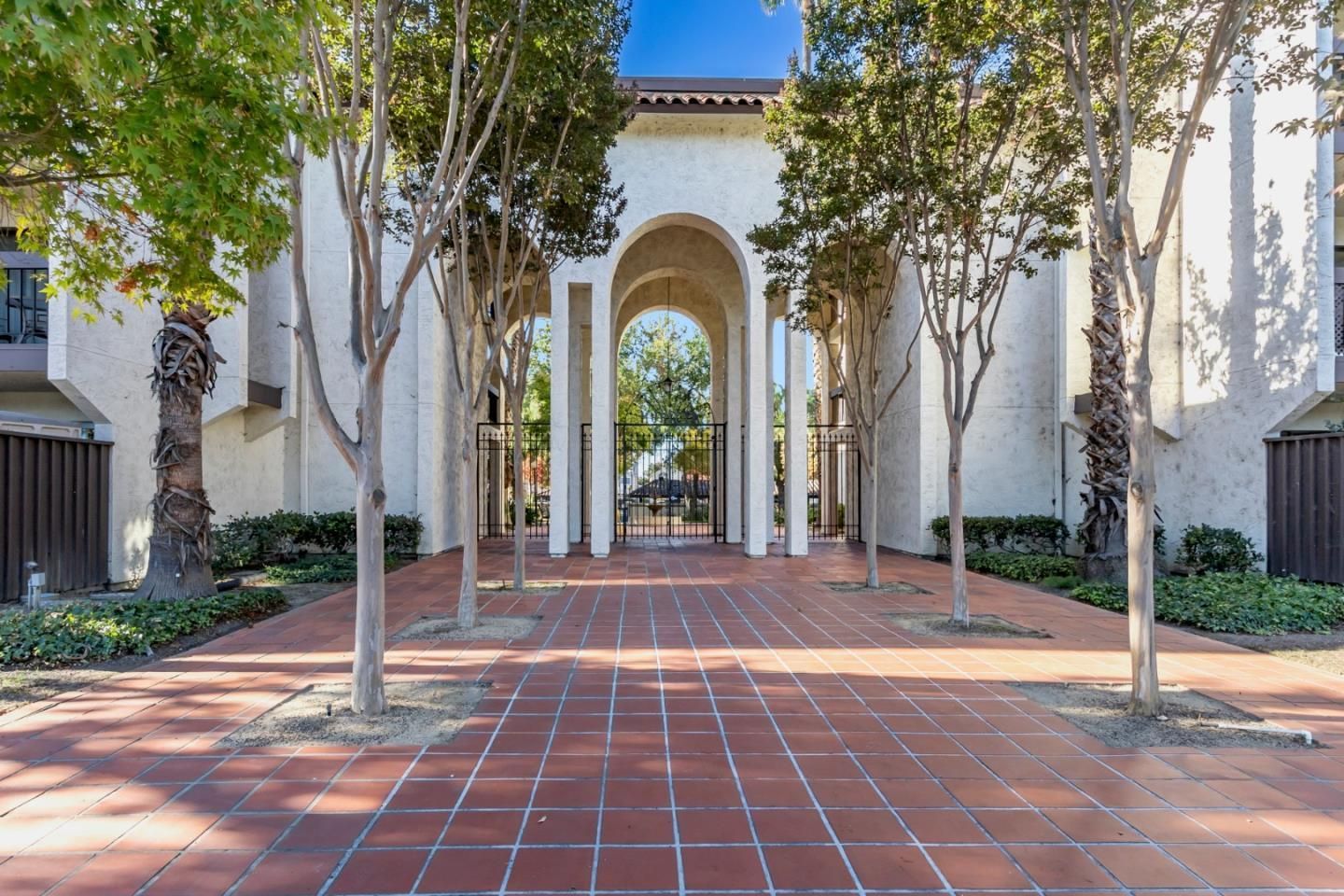 A brick walkway leading to a building with trees in front of it.