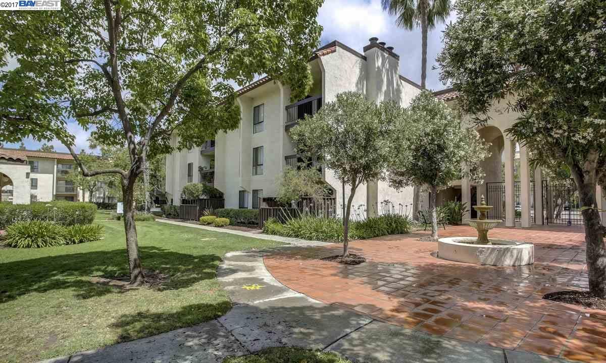 A large white building is surrounded by trees and a brick walkway.