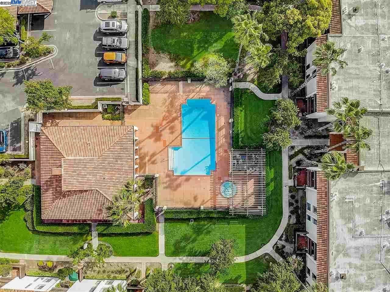 An aerial view of a swimming pool surrounded by trees and buildings.