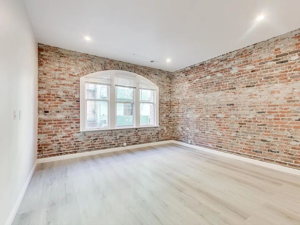 An empty room with a brick wall and a window