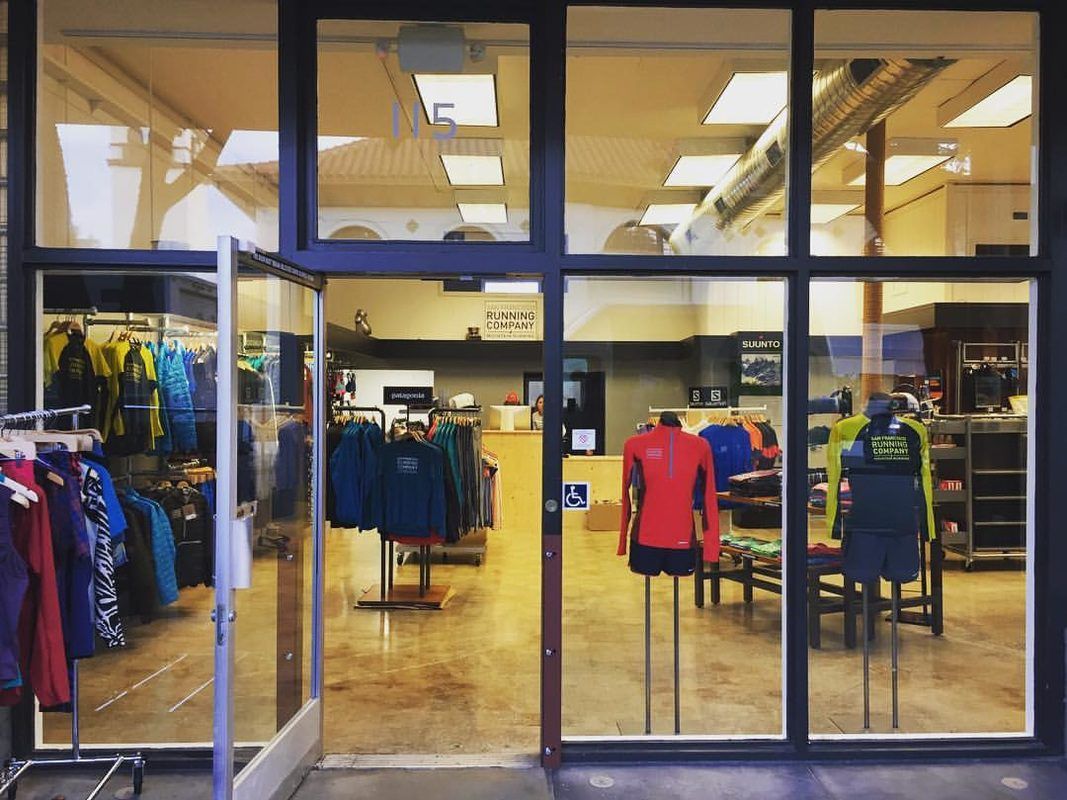 A store front with a lot of windows and clothes on mannequins.