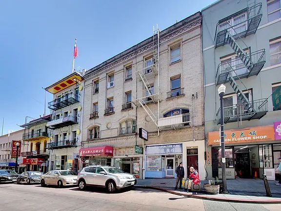 A row of cars are parked in front of a building in a city.