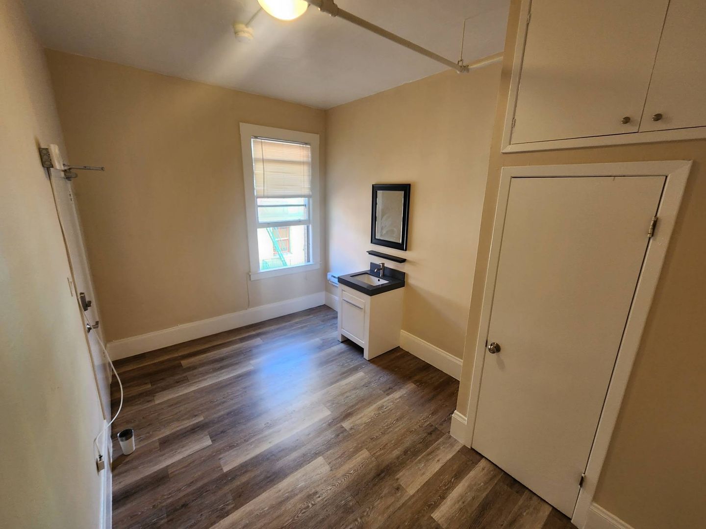 A small room with hardwood floors and a window.