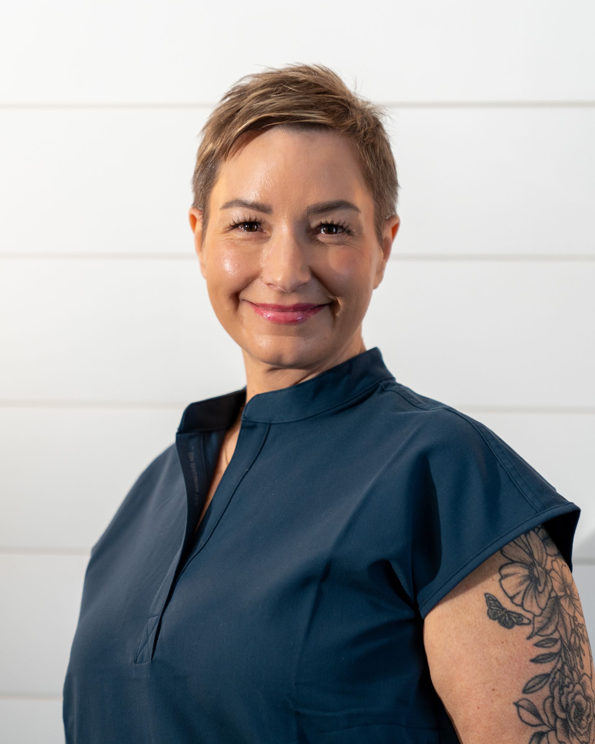 A woman wearing a black shirt and a necklace is smiling for the camera.