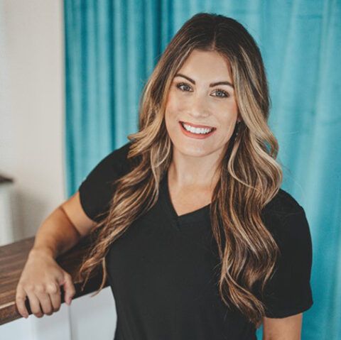 The woman is wearing a black shirt and smiling for the camera.