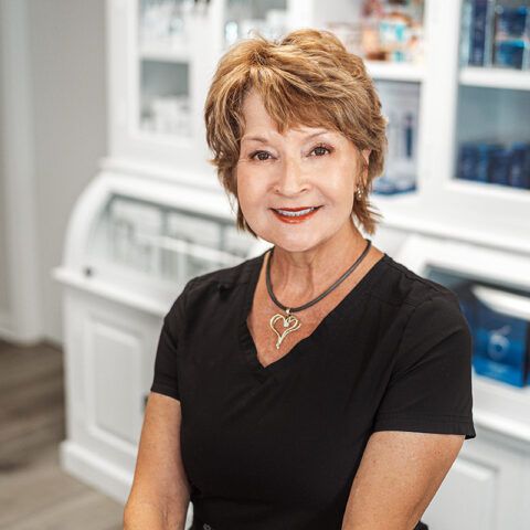 A woman wearing a black shirt and a necklace is smiling for the camera.