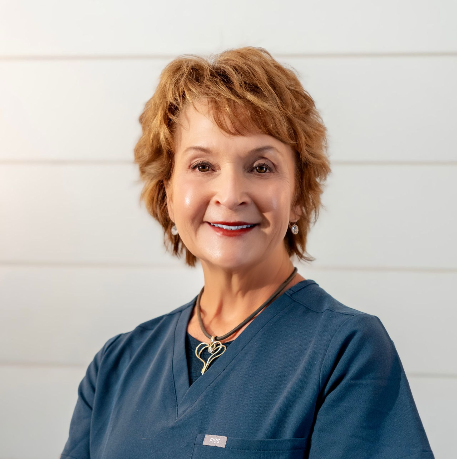 A woman wearing a black shirt and a necklace is smiling for the camera.