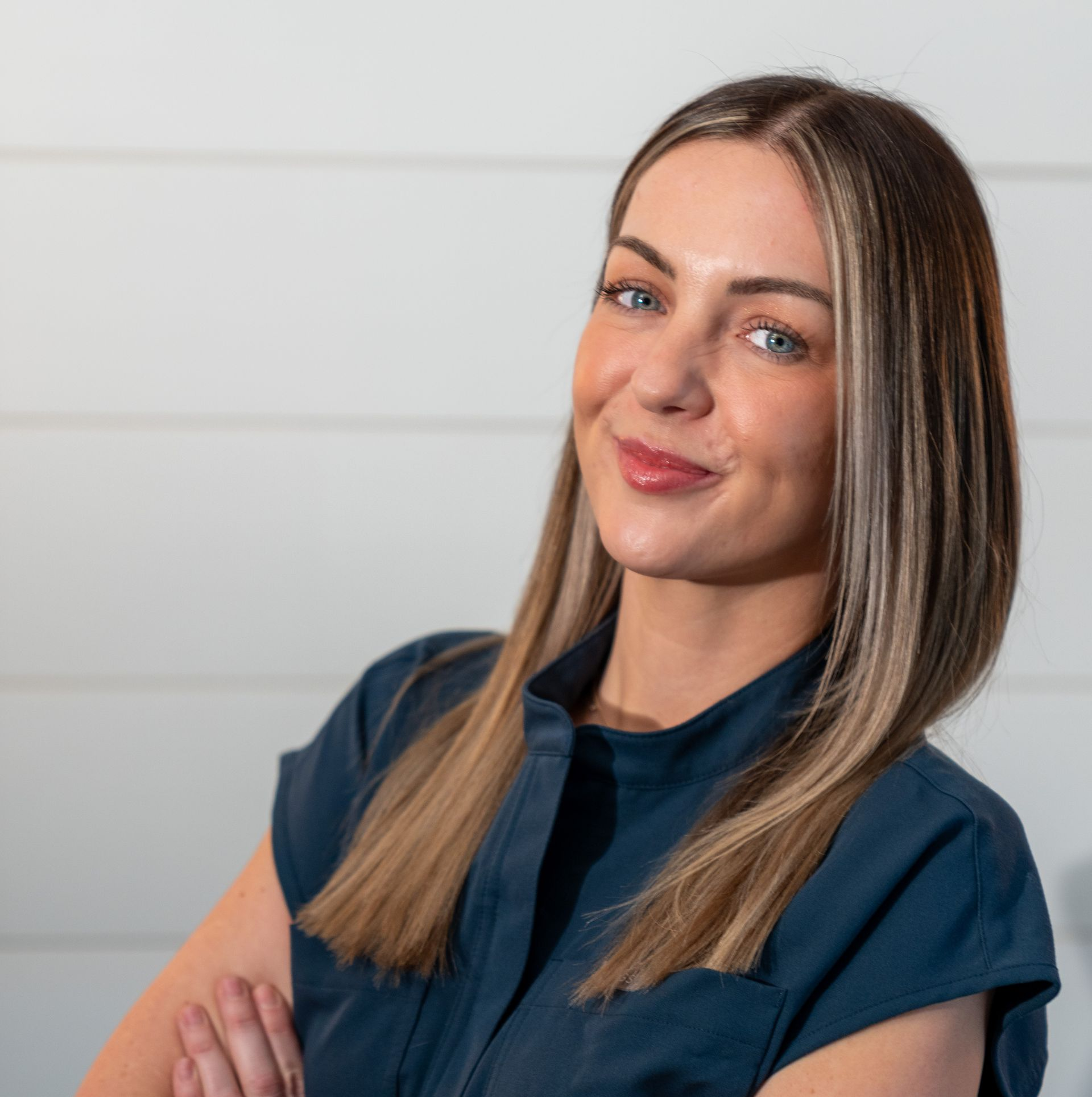 A woman wearing a black shirt and a necklace is smiling for the camera.