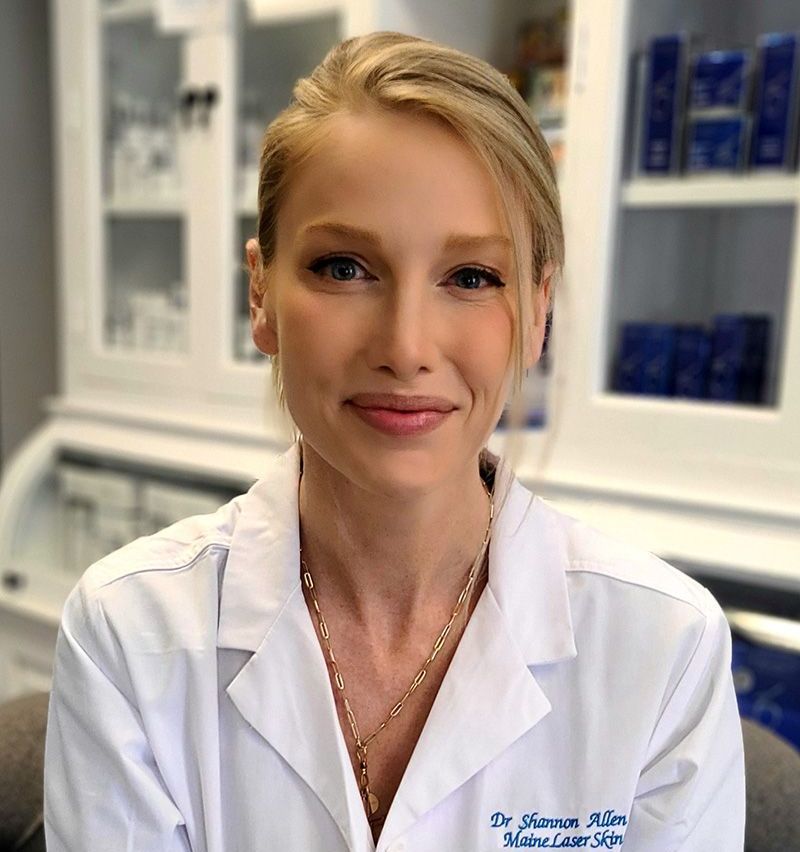 A woman in a white lab coat is smiling for the camera.