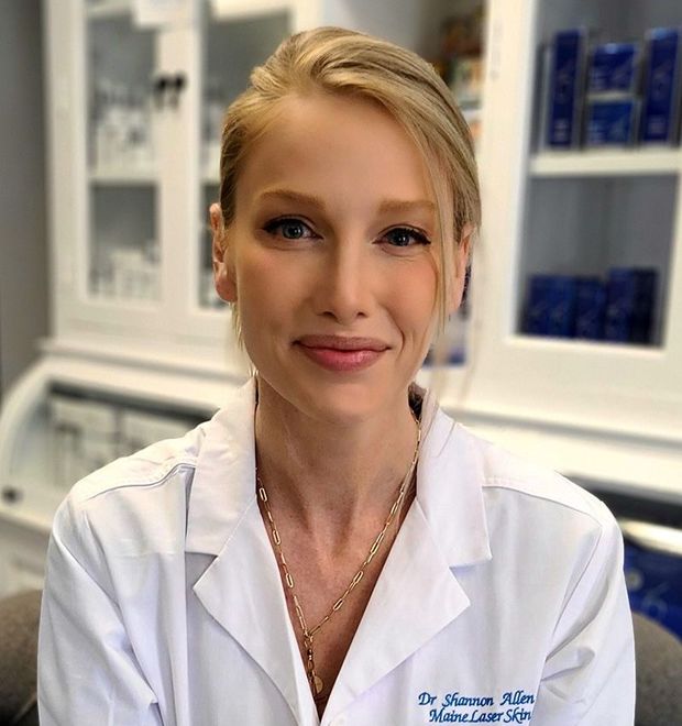 A woman in a white lab coat is smiling for the camera.