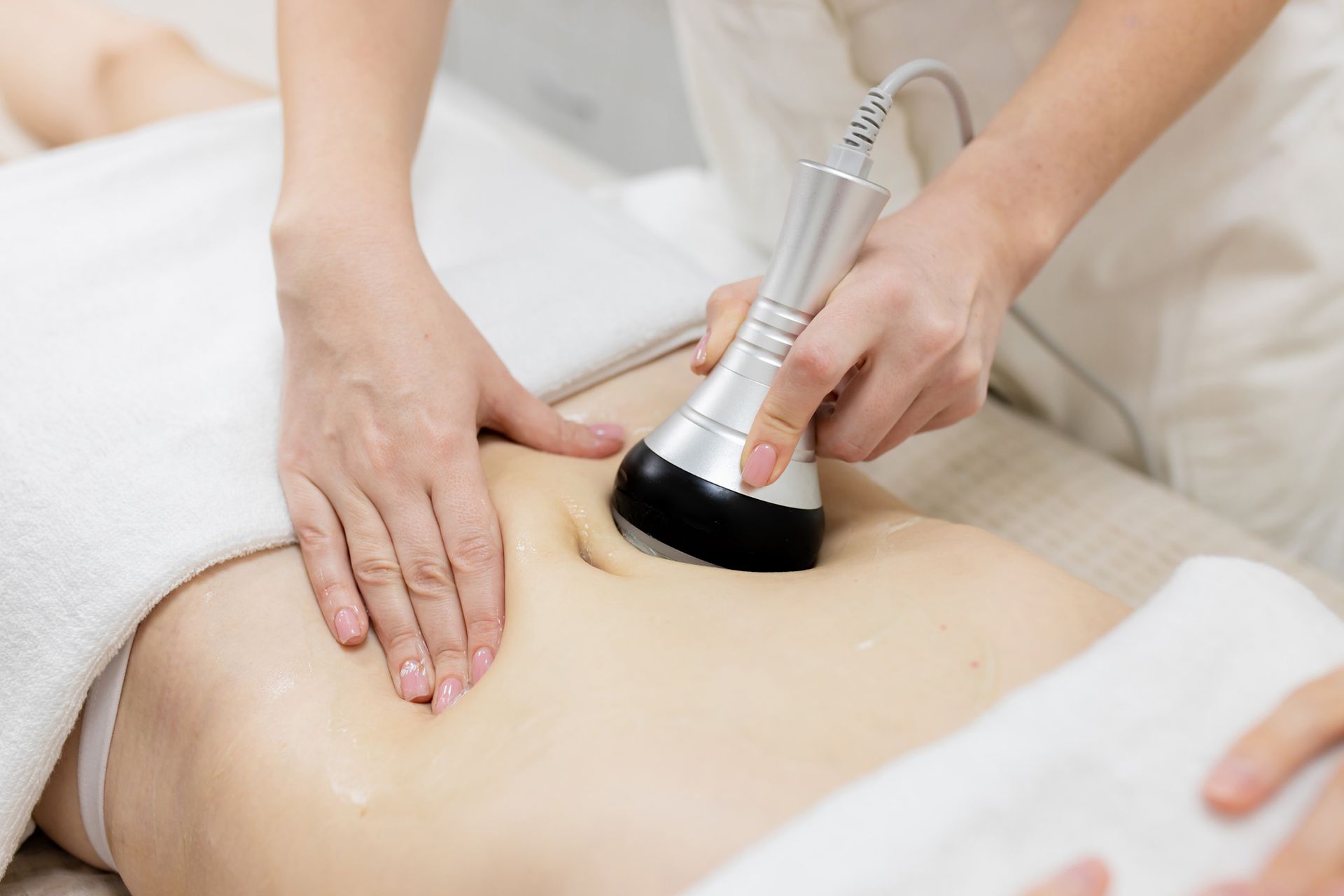 A woman is getting a cavitation treatment on her stomach.