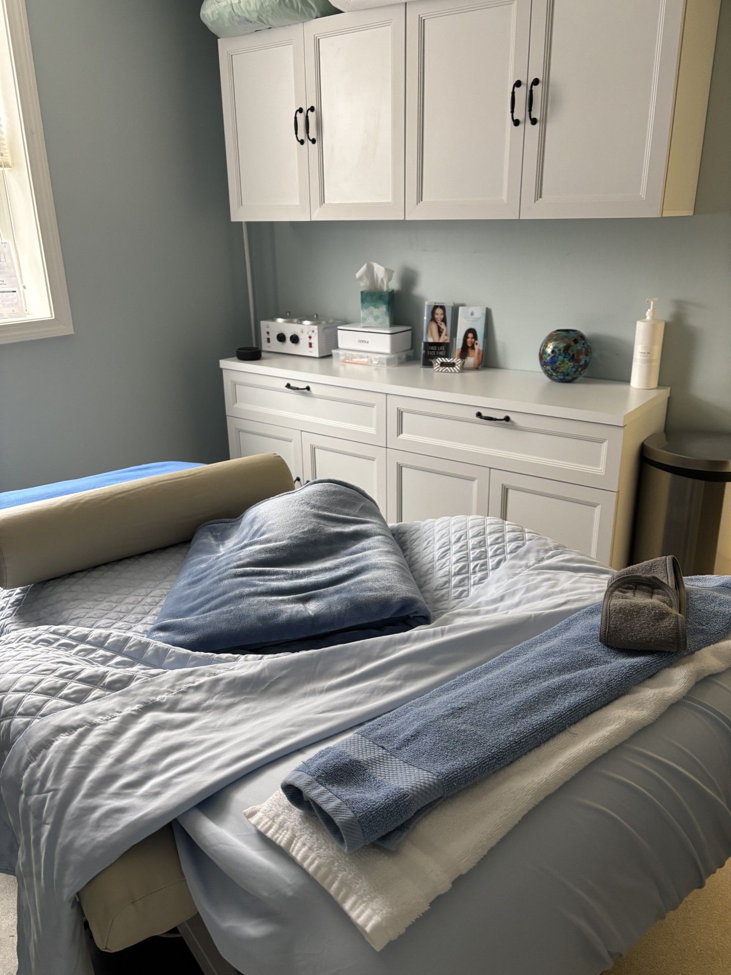 A bedroom with a bed , cabinets , and a trash can.