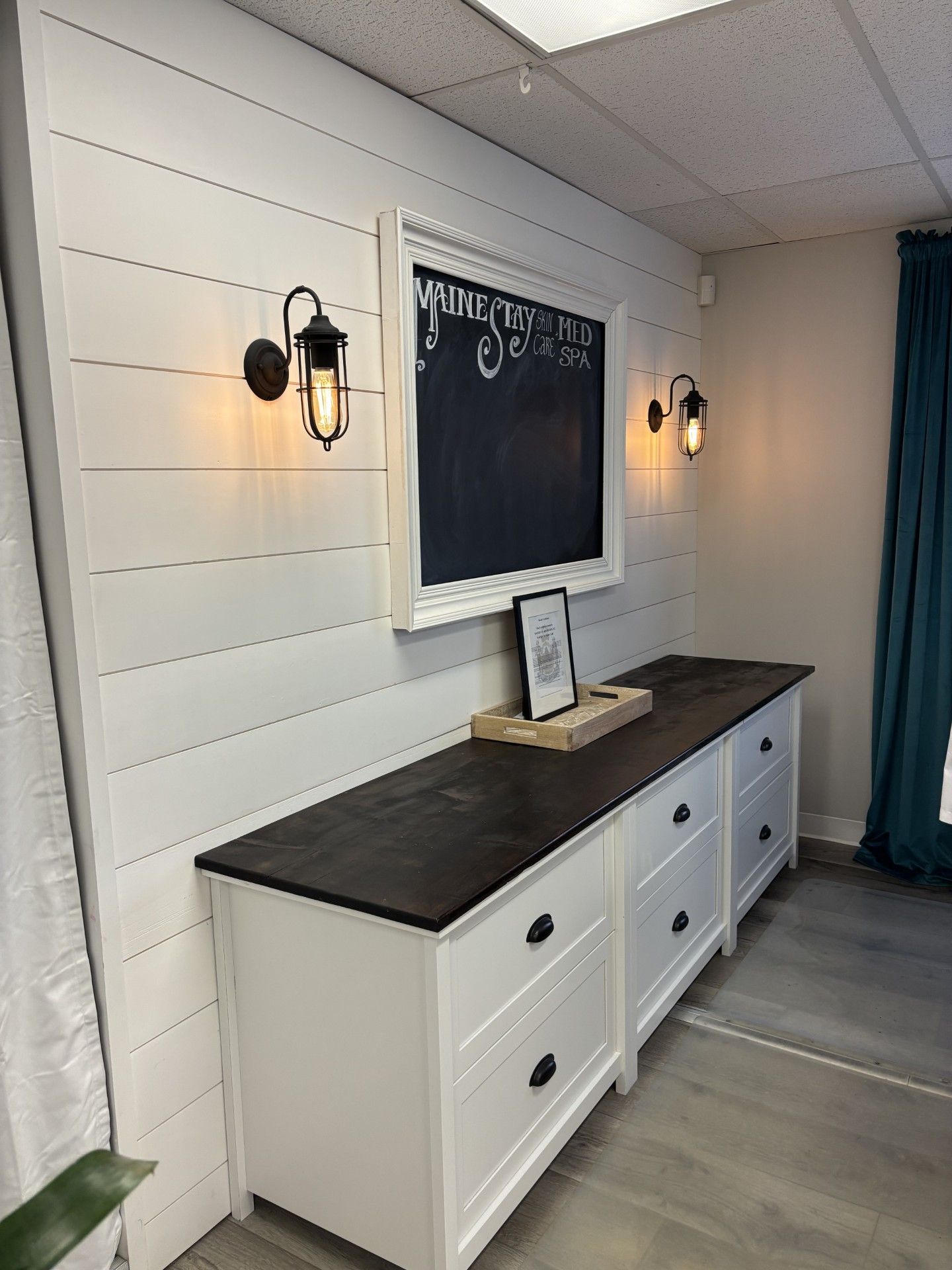 There is a chalkboard on the wall above the dresser.