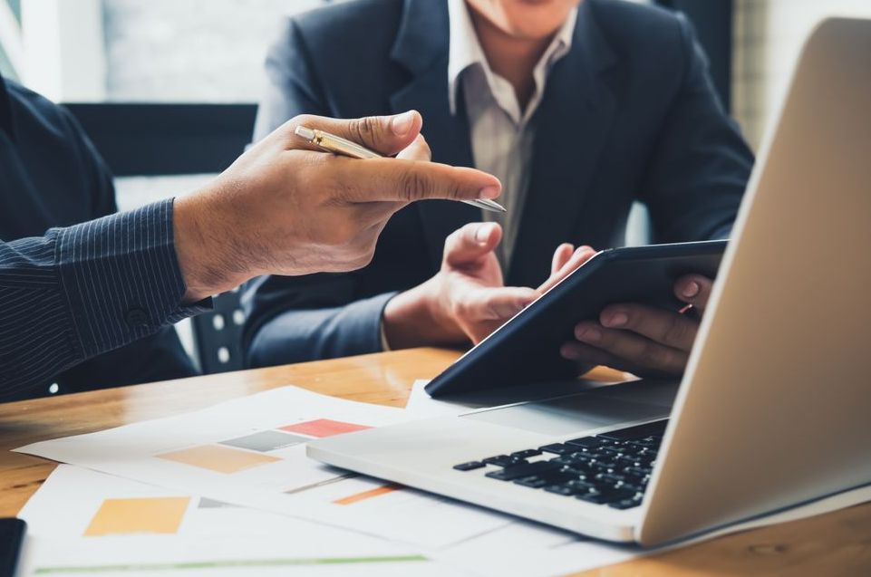 Two Men Are Looking at a Laptop and a Tablet — Townsville Accounting In Hyde Park, QLD