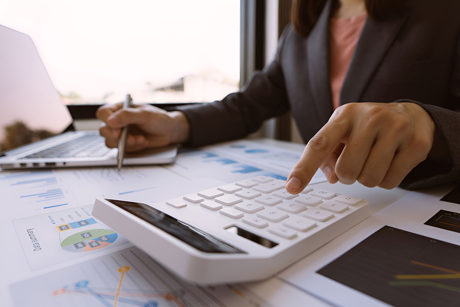 A Woman is Using a Calculator and Writing on a Piece of Paper — Townsville Accounting In Hyde Park, QLD