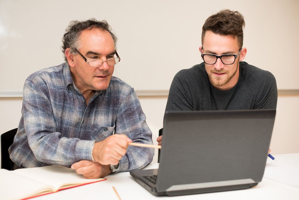 Two Men Are Sitting Looking at a Laptop Computer — Townsville Accounting In Hyde Park, QLD